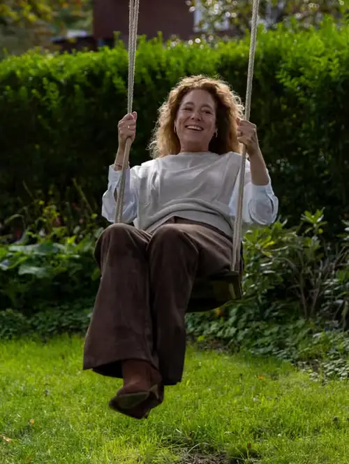 Suzanne op een schommel in de tuin
