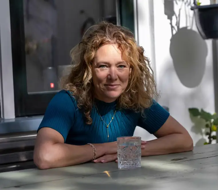 Suzanne leunend op een tuintafel, kijkend in de camera