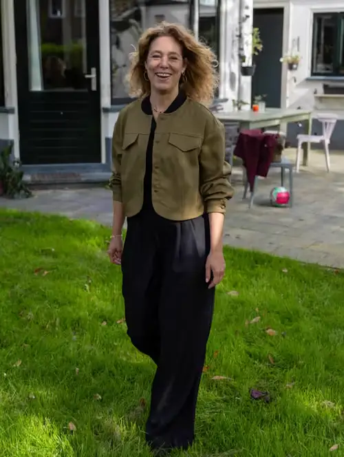 Suzanne lachend op het gras voor een wit huis